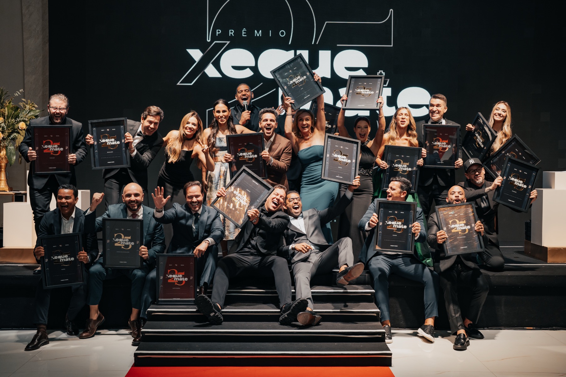 Vencedores da 3ª edição do Prêmio Xeque Mate com os troféus no palco